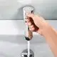 Armatur in chromfarbener Ausführung mit Wasserstrahl, hergestellt von CLAGE. Die Hand wird benutzt, um den Wasserfluss zu steuern, während das Wasser in das Waschbecken fließt.